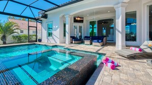 A swimming pool with a glass ceiling, outdoor seating, and a patio area.