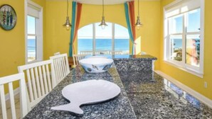 A room with a view of the sea, a white bathtub, and a dining area with a white railing. - "Seas the Day" (Week or Month) on Ormond Beach with  Pool and Ocean Views (Ormond Beach)