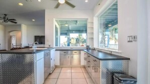 A modern kitchen with a central island, a ceiling fan, and a view of the outdoors. - "Seas the Day" (Week or Month) on Ormond Beach with  Pool and Ocean Views (Ormond Beach)