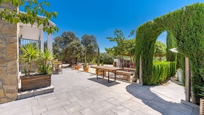 An outdoor patio area with stone flooring, wooden tables, and planters with various plants. - La Pedriza de Loja by Ruralidays (Granada)
