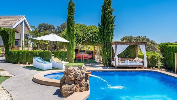 A swimming pool with a rock feature, a covered seating area, and a lounge chair. - La Pedriza de Loja by Ruralidays (Granada)