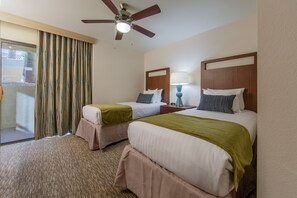 A hotel room with two beds, a ceiling fan, a window with curtains, and a nightstand with a lamp. - Comfortable 3 Bedroom Villa | Close to Golf Course (Scottsdale)