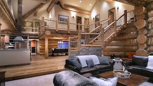 A spacious living area with a fireplace, a staircase, and a dining area. - Red Feather Ranch (Crested Butte)