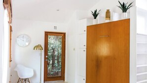 Ein modernes Zimmer mit einem Holzschrank, einem weißen Stuhl, einer Stehlampe und einer Tür mit Milchglasfenster.