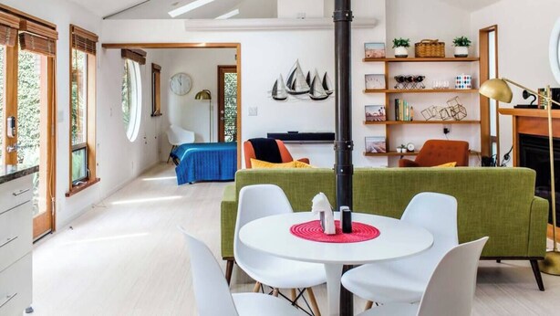 Ein modernes Wohnzimmer mit einem runden Tisch, weißen Stühlen, einem grünen Sofa und einem Kamin.