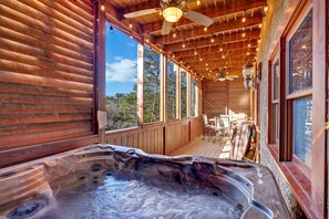 A wooden cabin with a hot tub and a deck with outdoor furniture.