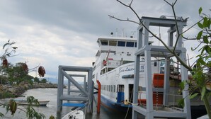 Un ferry atracado en el muelle, con un bote pequeño al frente.