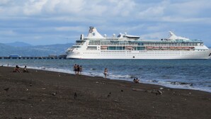 Un gran crucero atracado en un muelle, con una playa al frente.