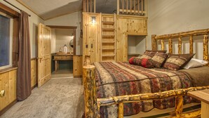 Ein Schlafzimmer mit einem hölzernen Bett, einem Schlafpodest, einem Schreibtisch und einem Stuhl.