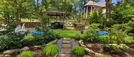 A garden with a gazebo, seating area, and a stone pathway leading to a pool.