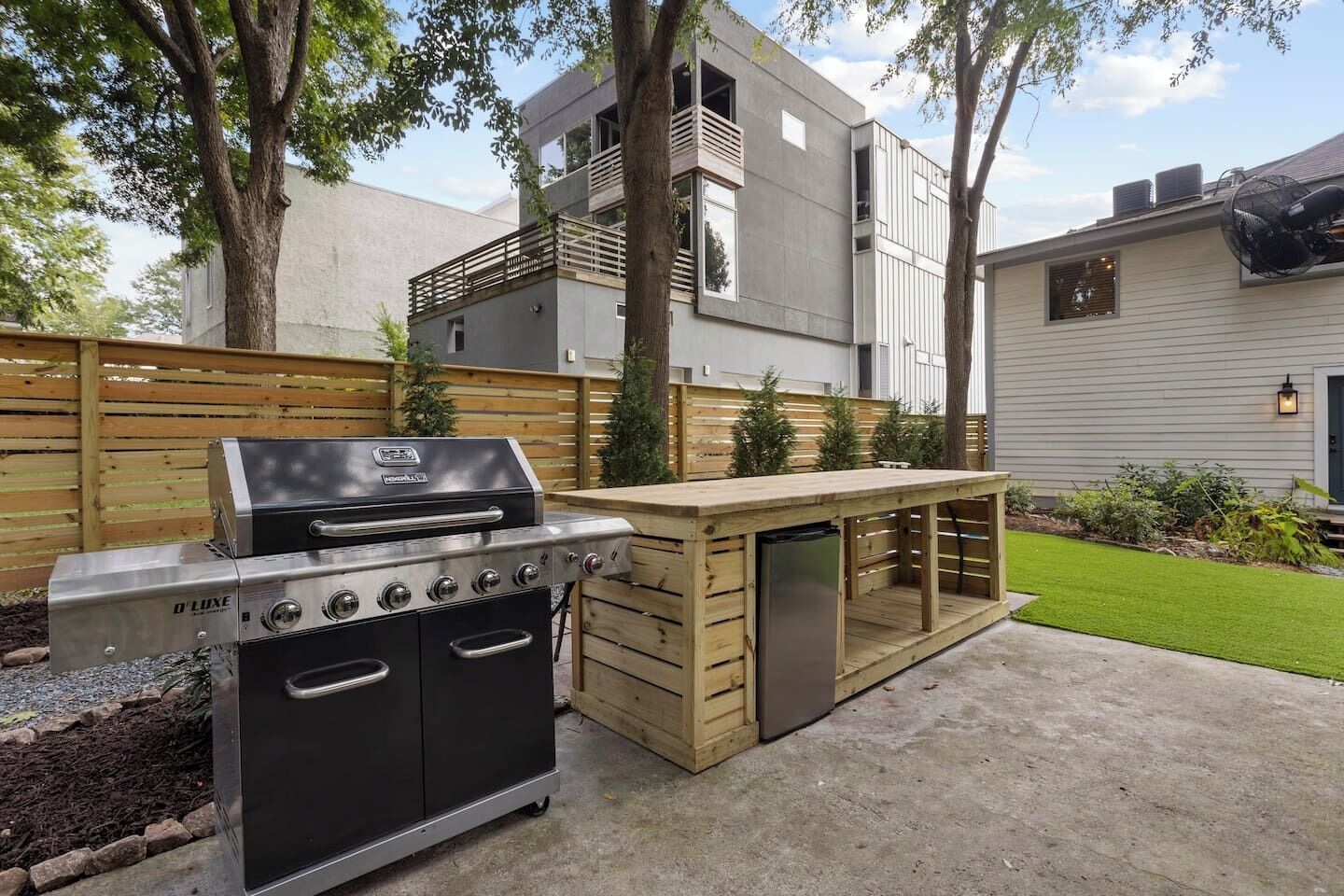 Un espace cuisine extérieur doté d’un barbecue intégré et d’une table en bois.