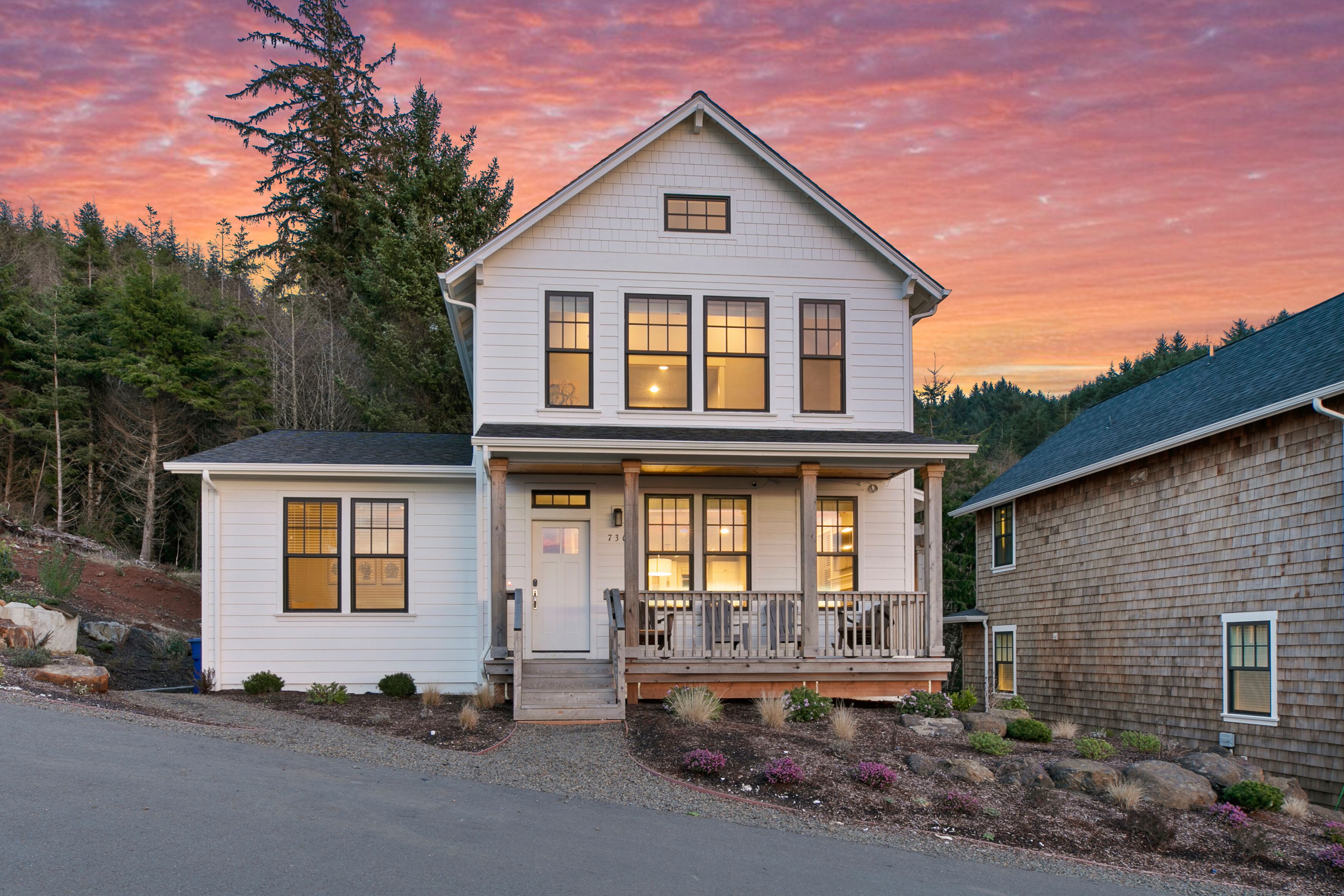 Une maison à deux étages avec un porche à l’avant, un garage et une allée.