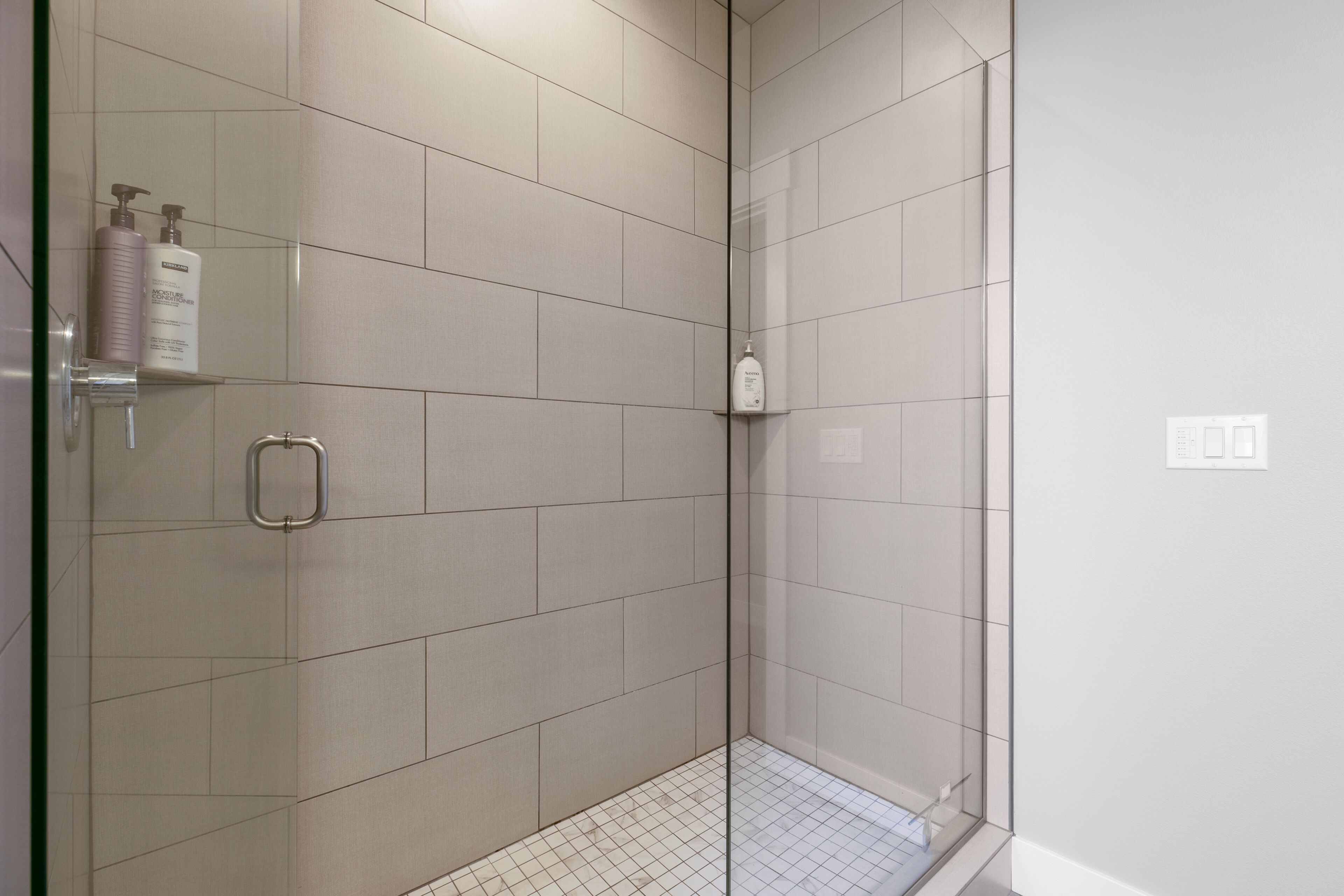 Un espace douche moderne avec des murs carrelés et une porte en verre.