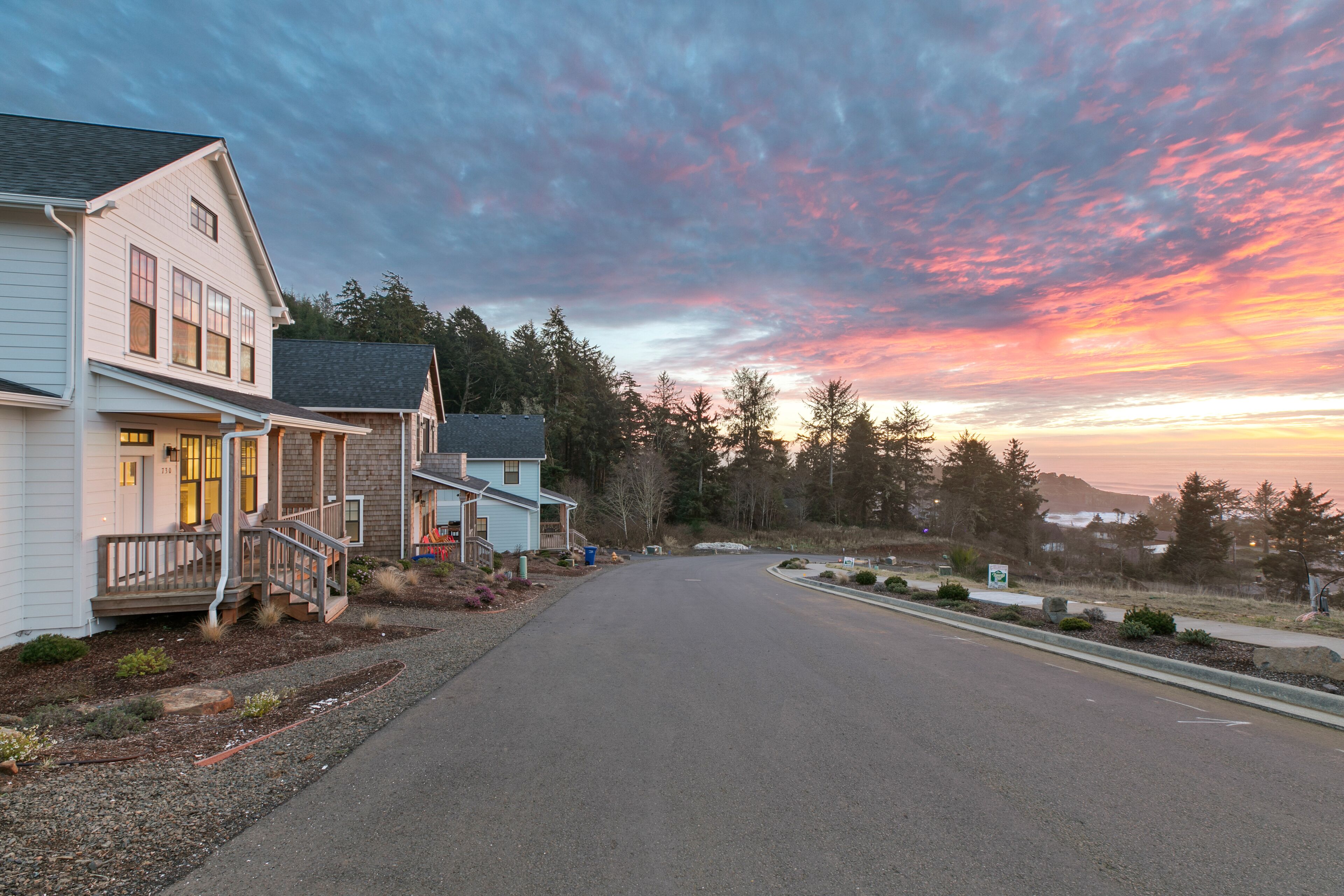 A residential street with houses, a clear sky, and a sunset.