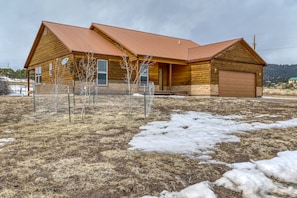 Situated in a rural setting, this cabin features a garage door and a chain-link fence surrounding the property.