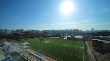 A sports field with a clear sky and city buildings in the background.