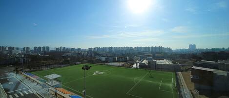 Un campo deportivo con un cielo despejado y edificios de la ciudad al fondo.
