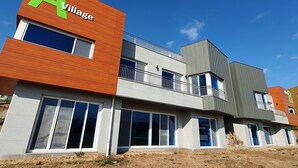 Een modern gebouw met een opvallend 'A Village' bord, grote ramen en een balkon.