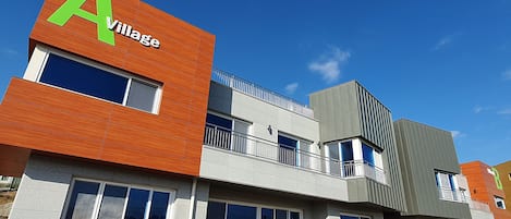 Un edificio moderno con un llamativo letrero que dice 'A Village', ventanas amplias y un balcón.
