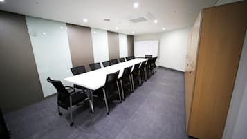 A conference room with a long table, chairs, a whiteboard, and a door.