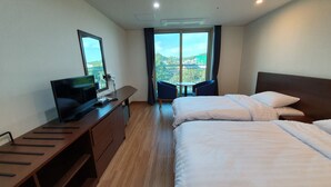 Een hotelkamer met een bed, een bureau met een televisie, een stoel en uitzicht op het omliggende landschap.