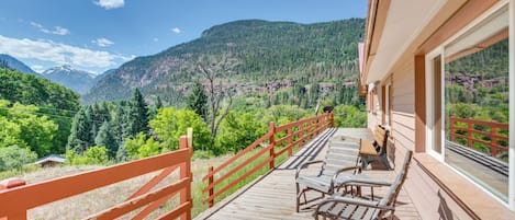 A wooden deck with benches overlooking a mountainous landscape.
