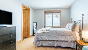 Quarto com cama, penteadeira, televisão, janela com vista para neve e porta.