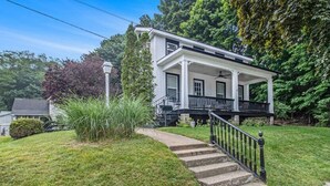 A two-story house with a porch, a front yard, and a staircase leading to the entrance. - Family Home Near Beach, Downtown, Marina (Manistee)
