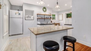 A modern kitchen with a central island, white appliances, and pendant lighting. - Family Home Near Beach, Downtown, Marina (Manistee)