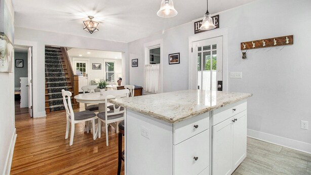 A kitchen with a marble countertop, white cabinetry, and pendant lighting. - Family Home Near Beach, Downtown, Marina (Manistee)