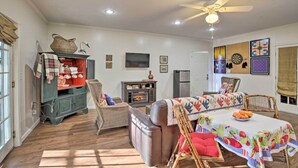 A cozy living room with a fireplace, a dining table with a colorful tablecloth, and a ceiling fan. - Cozy & Quiet Studio w/ Porch, Near Scenic Railway! (Blue Ridge)