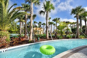 A swimming pool with palm trees and a green inflatable ring.