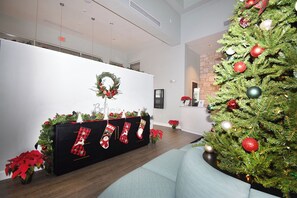 A lobby with a Christmas tree, a reception desk, and a wall with a wreath.