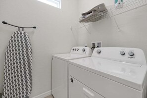A laundry room with a white washing machine, a dryer, and a hanging rack.