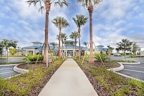 A pathway leading to a building with a blue roof, surrounded by palm trees and a landscaped garden. - Windsor Island Pool Home | Rare Backyard Privacy | 3 Master Suites | Game Room (Davenport)