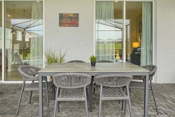 A dining area with a table and chairs, a potted plant, and a painting on the wall.