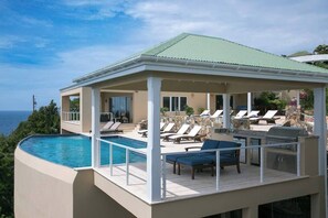 Ein Poolbereich mit Liegestühlen und einem Grill, mit Blick auf ein Gewässer.