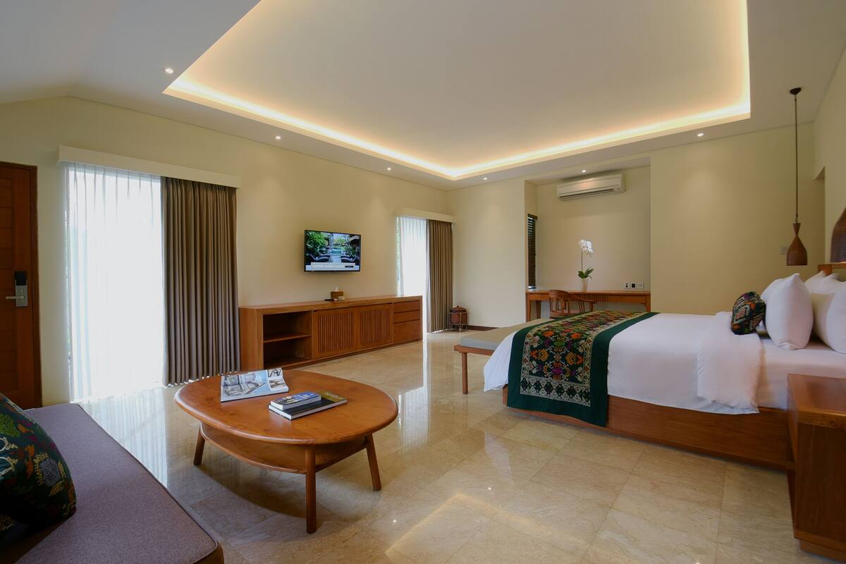 A hotel room with a bed, a TV, a desk, a coffee table, and a sofa.