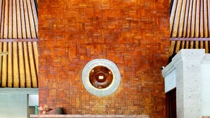 Pared de ladrillo con tragaluz circular y listones de madera a cada lado.