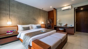 Una habitación de hotel moderna con una cama grande, mesitas de noche, un tocador con espejo y un equipo de aire acondicionado.