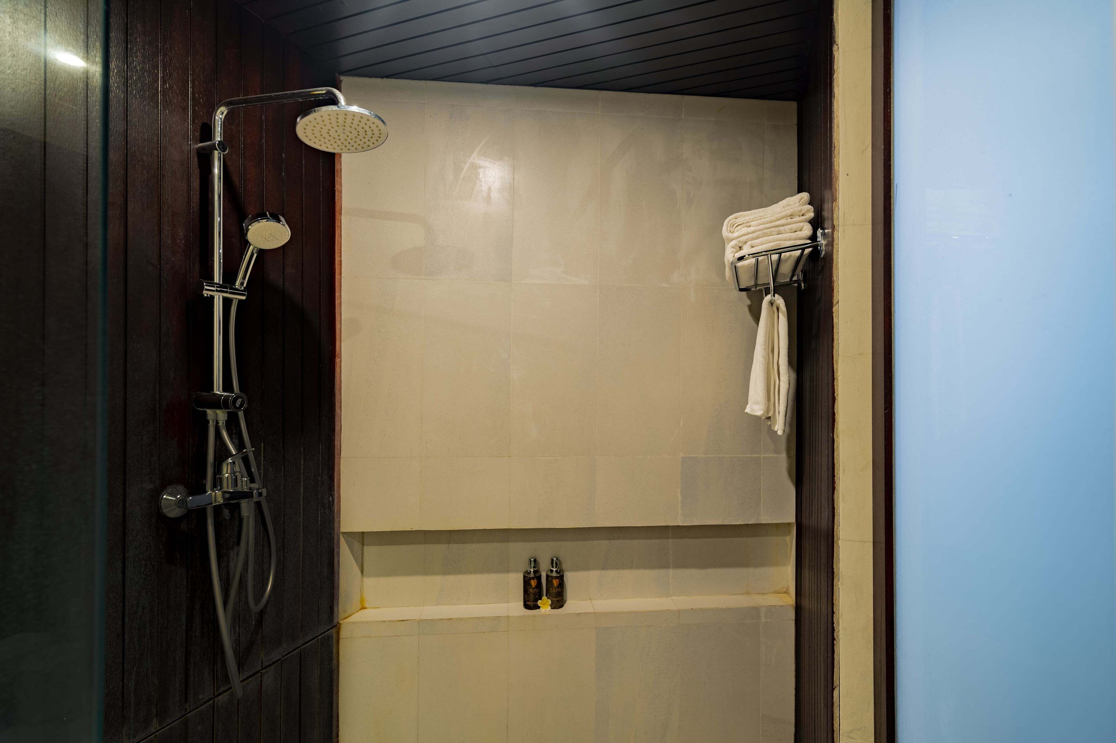 A modern bathroom with a shower, a towel rack, and a shelf with toiletries.