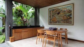 Un área de comedor con una mesa y sillas de madera, una encimera negra y un cuadro grande en la pared.