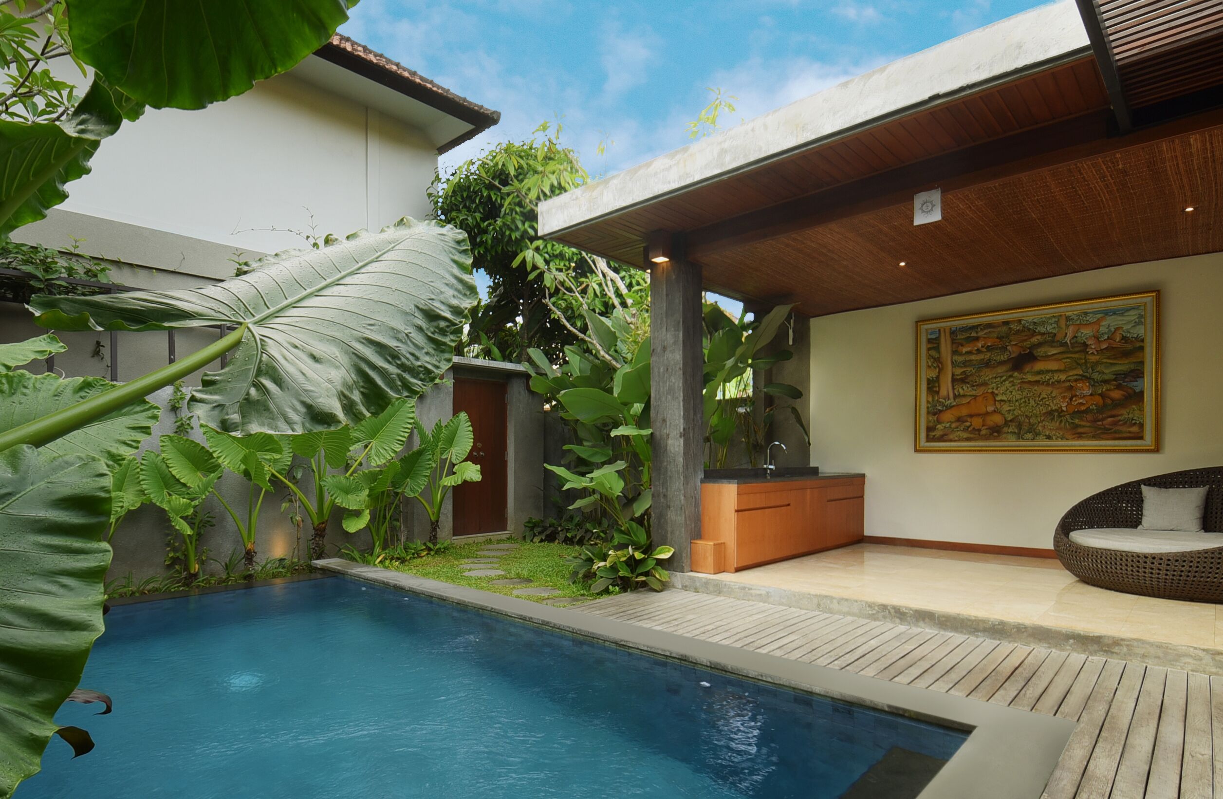 Piscina com deck de madeira, cercada por plantas tropicais.