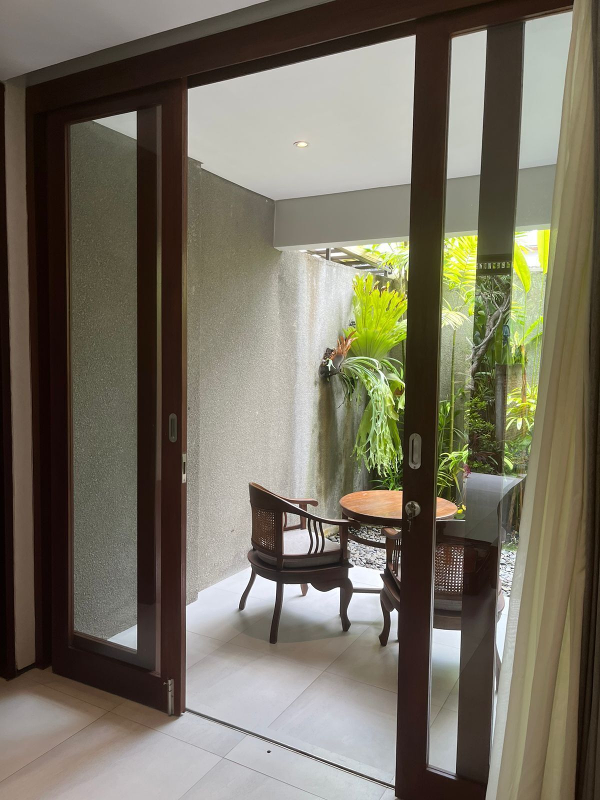 Una habitación con puerta de cristal corredera que da a un balcón con mesa y sillas.