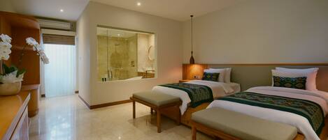 A hotel room with a large mirror, a shower, two beds with matching headboards, a bench, and a wooden dresser.