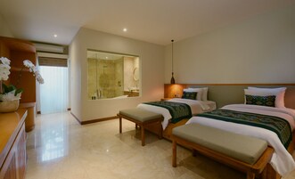 A hotel room with a large mirror, a shower, two beds with matching headboards, a bench, and a wooden dresser.