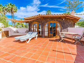 A patio with a stone wall, a wooden door, and a seating area with a table and chairs.