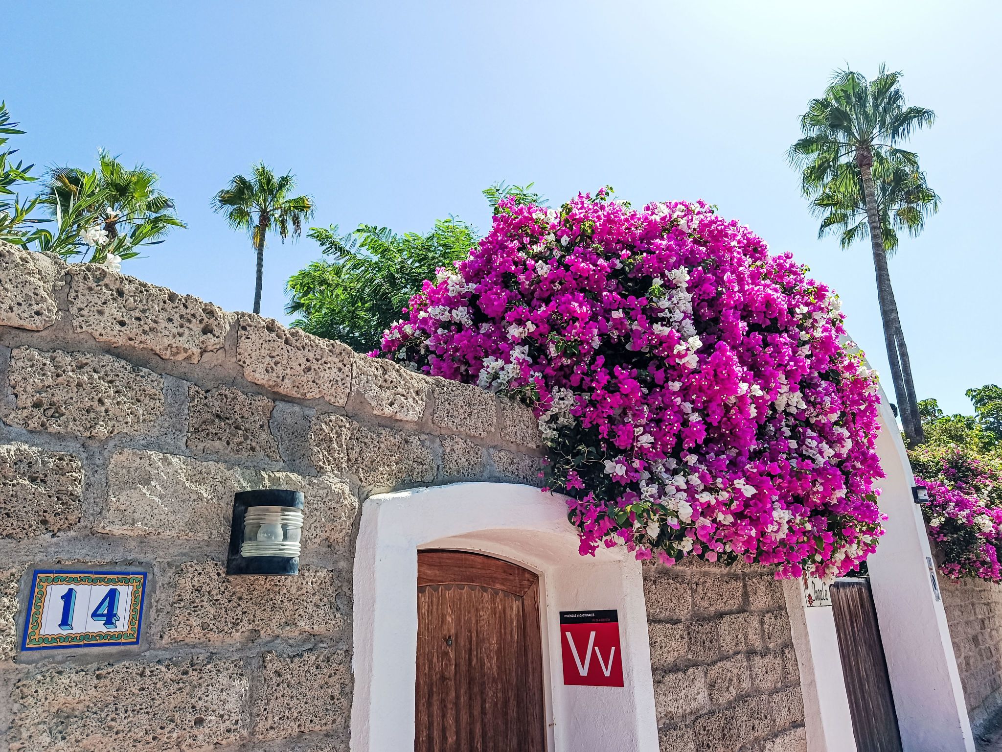 A stone building with a wooden door and a sign with the letter 'W'.