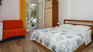 A bedroom with a bed, a chair, a wardrobe, and a window with curtains.