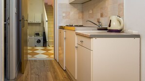 A compact kitchen with a sink, kettle, and a washing machine in the background.